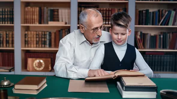 70s Grandfather and Kid Boy Reading Textbook Explaining Talking Feeling Love at Retro Public Library