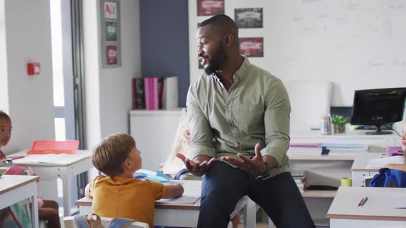 Video of happy african american male teacher during lesson with class of diverse pupils