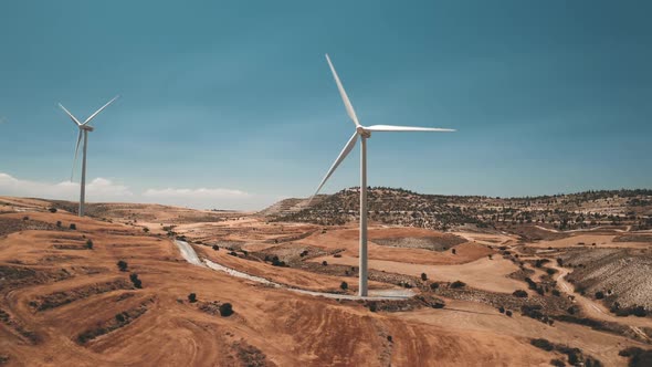 Aerial Wind Turbines Rotate in Desert Against Blue Sky alt