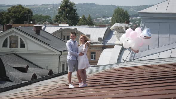 Couple with balloons standing on a roof