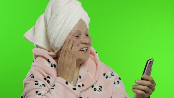 Elderly Grandmother in Bathrobe. Old Woman Using Mobile Phone for Video Call