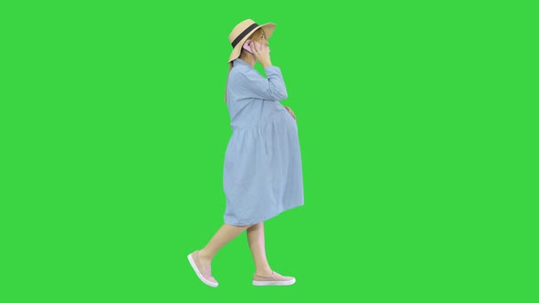 Beautiful Caucasian Pregnant Woman Making a Call on Summer Walk Outdoors on a Green Screen, Chroma