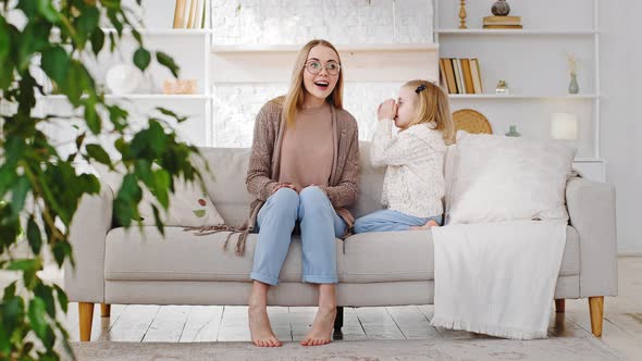 Little Preschool Girl Child Daughter Covers Mouth with Hands Whispers Talks Tells Quietly Secret