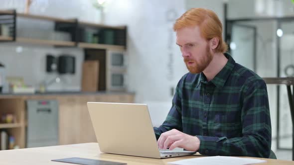 Beard Redhead Man Reacting to Loss on Laptop in Cafe