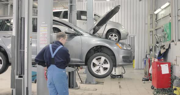 The Car Goes Down On The Lift In The Auto Repair Shop