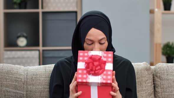 Portrait of Shocked Ethnic Muslim Woman Open Red Giftbox with Desired Present Posing at Home