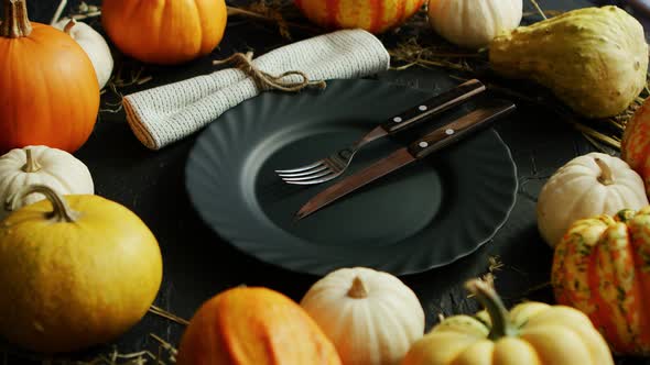 Black Plate and Cutlery Surrounded By Pumpkins