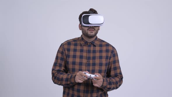 Young Bearded Indian Hipster Man Playing Games and Using Virtual Reality Headset