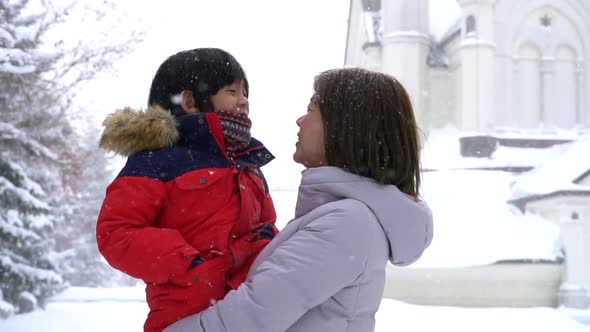 Asian Mother And Son Enjoying Snowy Winter Day Outdoors