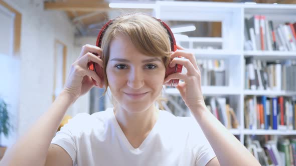 Smiling Young Woman Wearing Headphones to Listen Music