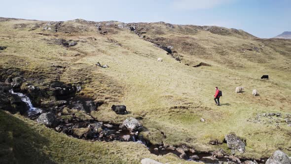Sunny Cliff and Grasslands and Stream of Water with Man Exploring Scenic Area