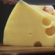 Person Cuts Tasty Hard Cheese with Large Holes on Board - VideoHive Item for Sale