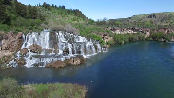 Flying view of waterfall flowing over edge into river