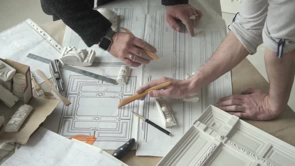 Hands of Two Male Designers Working on Molding Blueprint