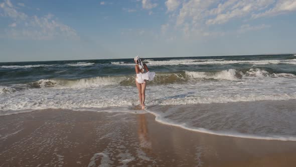 Brunette Woman in a White Swimsuit Walk Along a Sandy Beach