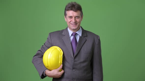 Mature Handsome Businessman Against Green Background