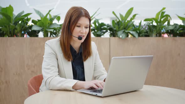 Call Center Manager Talking on Headset and Using Laptop