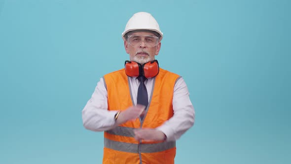 Man Engineer in Protective Uniform Makes a Gesture of the Cross with Hands and Says No Looking at