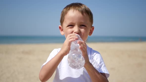 The Child Enjoys Drinking Water From a Transparent Plastic Bottle, and Then Smiles