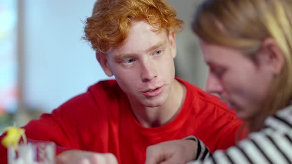 Closeup Portrait of Young Redhead Caucasian Man Sitting with Friend in Bar Talking