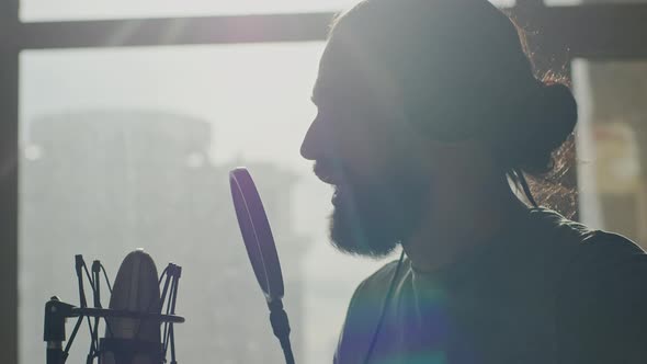 A Young Male Radio Presenter Reads a Text in Front of a Microphone