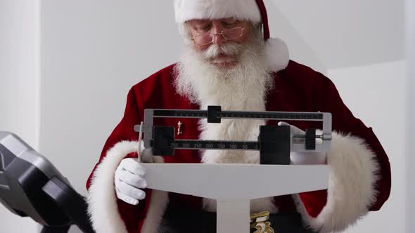 Santa Claus looks at weight on scale alt