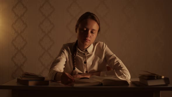 Young woman sitting at the table, flipping pages of encyclopedia, read a book, study at home library