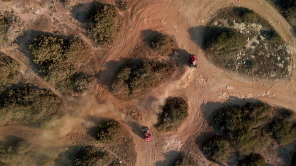 Aerial view looking down on two ATV dune buggies race and then leave the path in Cavo Greko