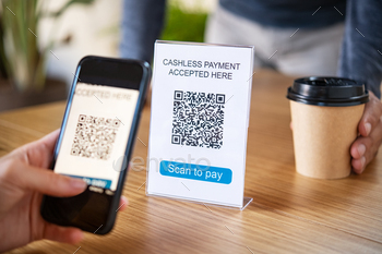 . Close up of woman hand holding smartphone and scanning qr code for cashless payment at cafeteria. Girl  framing qr code in coffee shop to make a purchase, small business accepts digital payment.