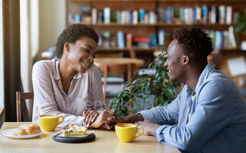 Romantic black couple having breakfast together at cafe, holding hands and looking at each other / Photodune, Misc