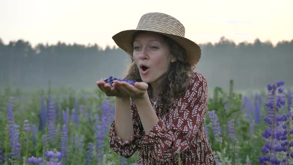 Curly Woman Stands in Lupine Field in the Fog, Girl Blows Off the Lupine Petals, Slow Motion