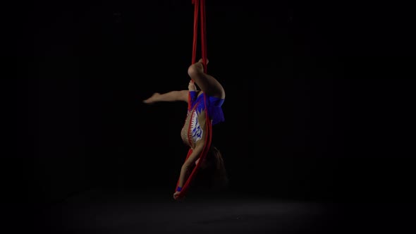 Female Aerial Gymnast Performing on a Red Silk in a Black Background