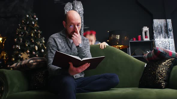 New Year - Dad Is Reading a Book and His Daughter Is Distracting Him