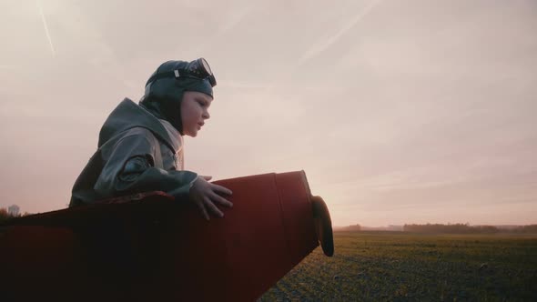 Side View Camera Follows Happy Little Pilot Boy in Fun Plane Costume Running in Amazing Sunset