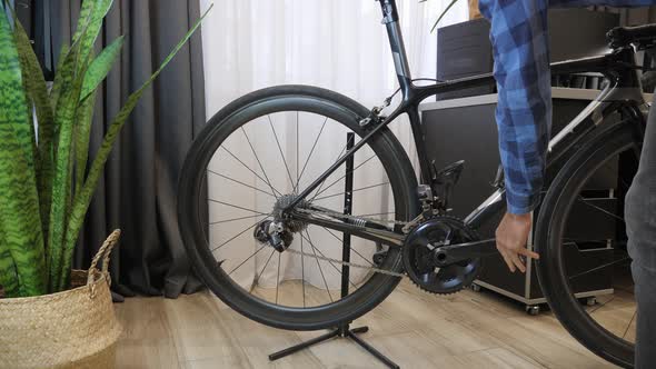 Bicycle mechanic puts bike on rack in bike workshop. 