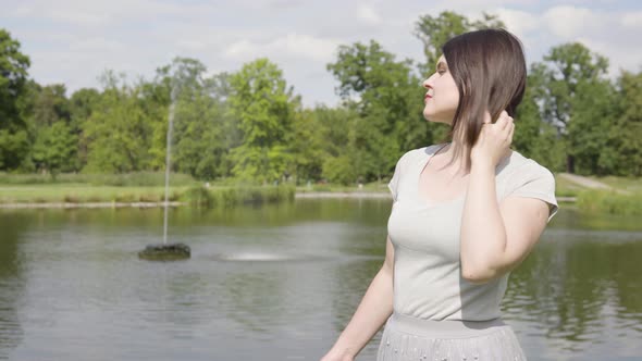 A Young Caucasian Woman Thinks About Something in a City Park on a Sunny Day