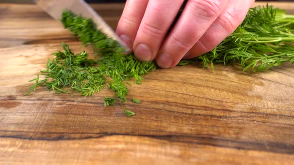 The cook cuts fennel on a wooden cutting board.