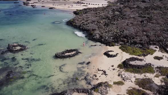 Aerial drone footage of a guy chilling in a nice beach with turquoise waters in Lanzarote, Canary is