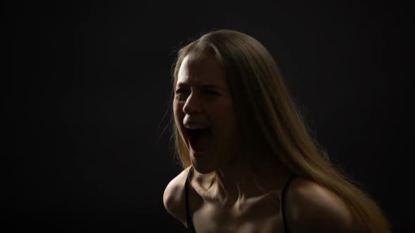 Woman Shouting Against Dark Background, Closing Mouth With Hand, Calming Down