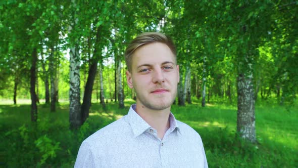 A Young Man Smiling in the Park in Summer