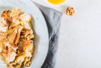 topped with walnuts, coconut yogurt and honey, grey background, top view