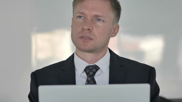 Close Up of Thinking Businessman Working on Laptop Frontal View