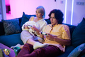 Couple of young adults playing video games at home. Emotional diverse gamers holding joysticks and - PhotoDune Item for Sale