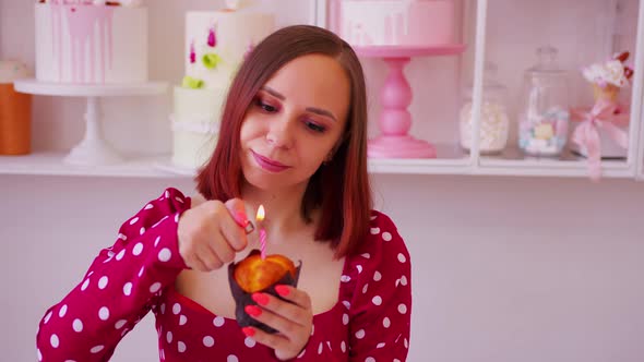Young Woman in Red Dress Lighting Candle in Muffin