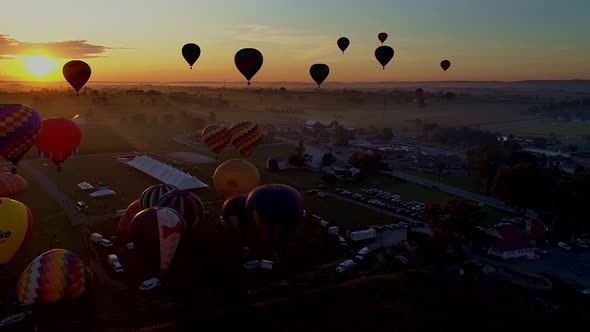 Aerial view of multiple hot air balloons early morning take off into the sun during a festival 