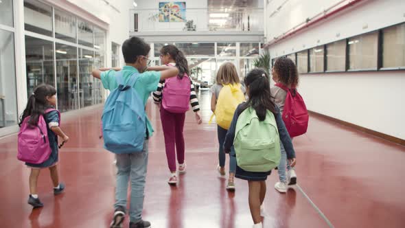 Cheerful Kids with Backpacks Walking Along School Hallway