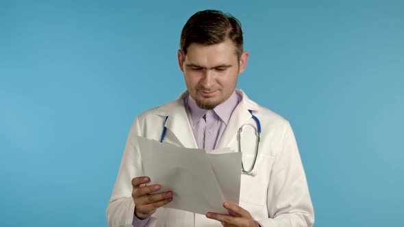 Satisfied Man in Professional Medical Coat Holding Files Papers Isolated on Blue Background, He Nods