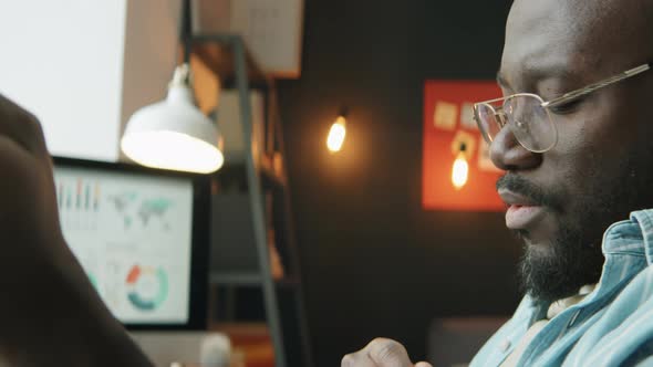 African American Man Listening to Music and Working on Laptop