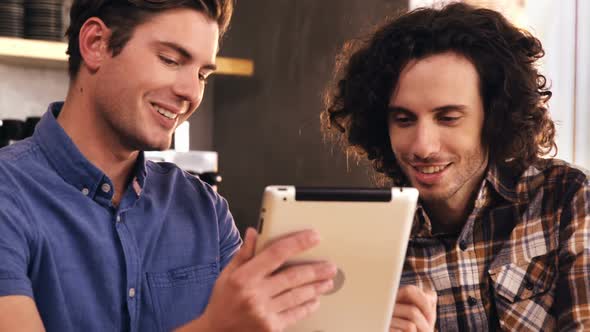 Two men using digital tablet in caf������������