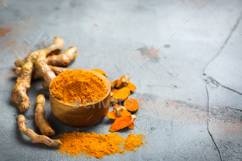 t. Raw organic orange turmeric root and powder, curcuma longa on a grunge cooking table. Indian oriental low cholesterol spices. Copy space background